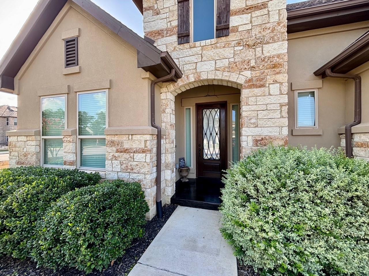 Natural stone accents and a concrete walkway fram