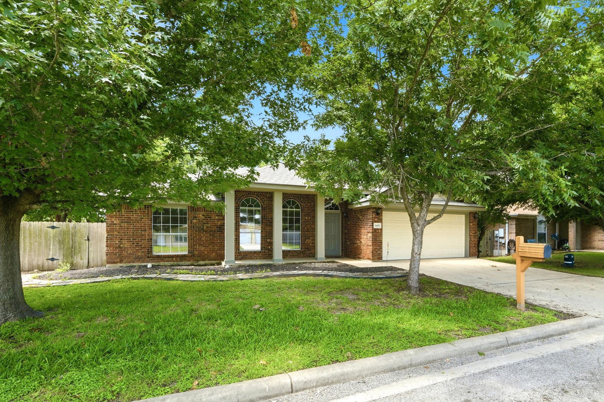 Mature trees shade a charming brick facade with a