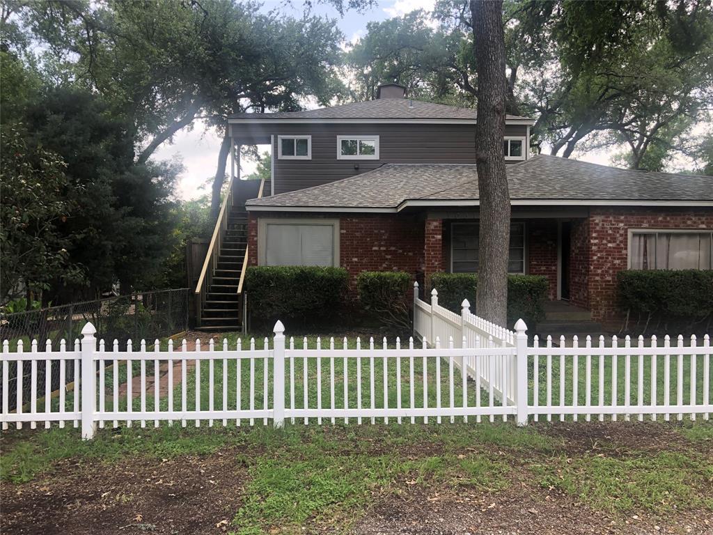 A charming brick residence features a picket fenc