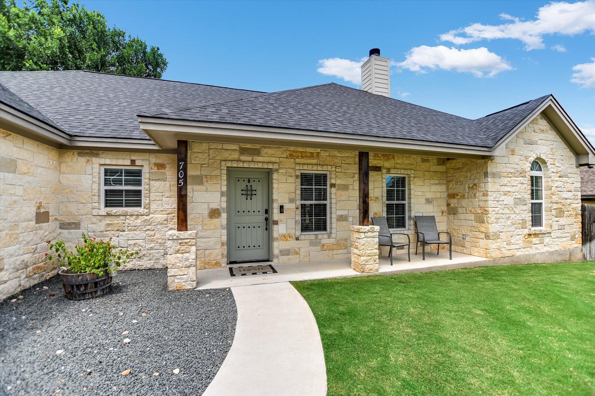 An inviting stone-faced home with a covered front