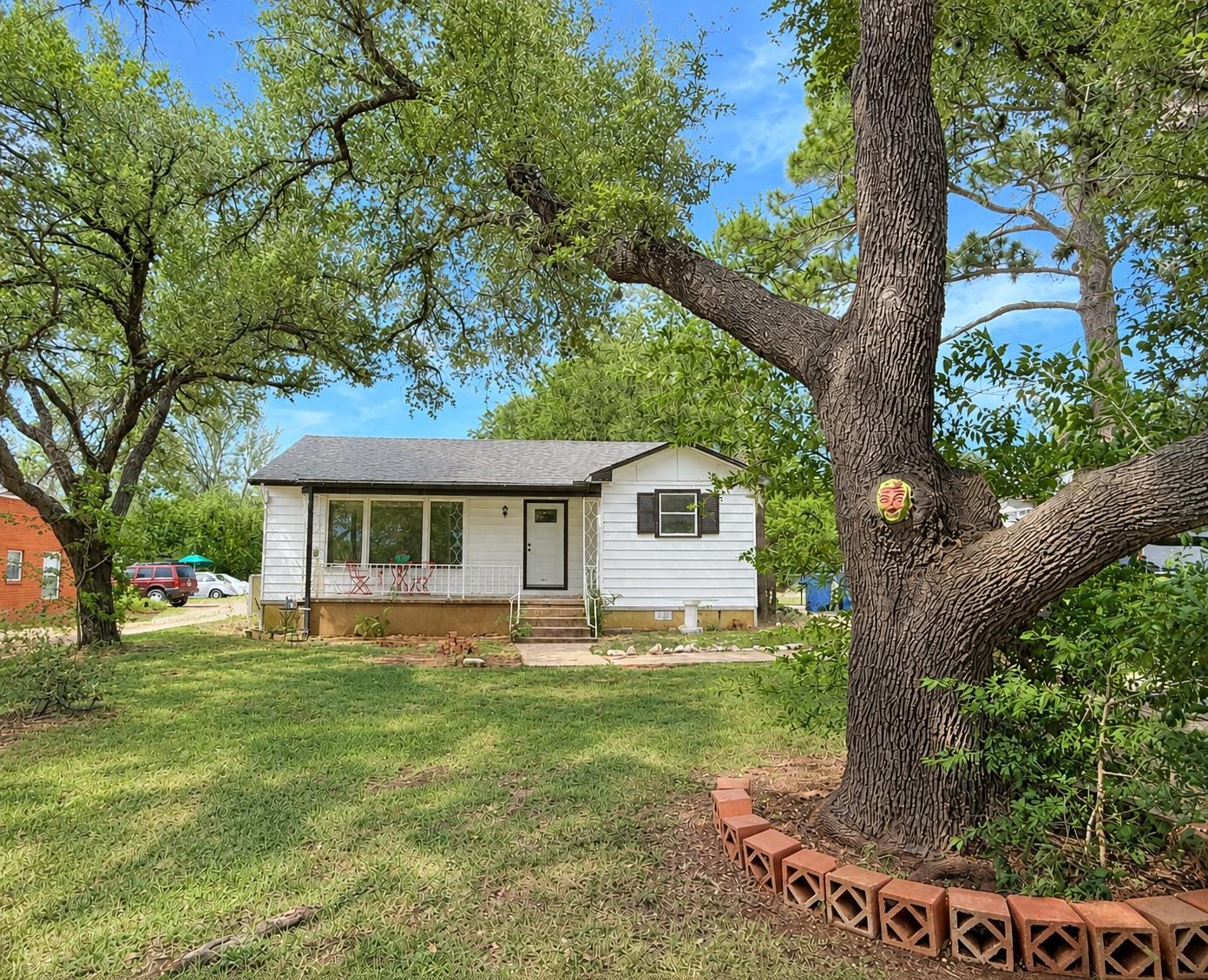 Mature shade trees frame the classic siding exter