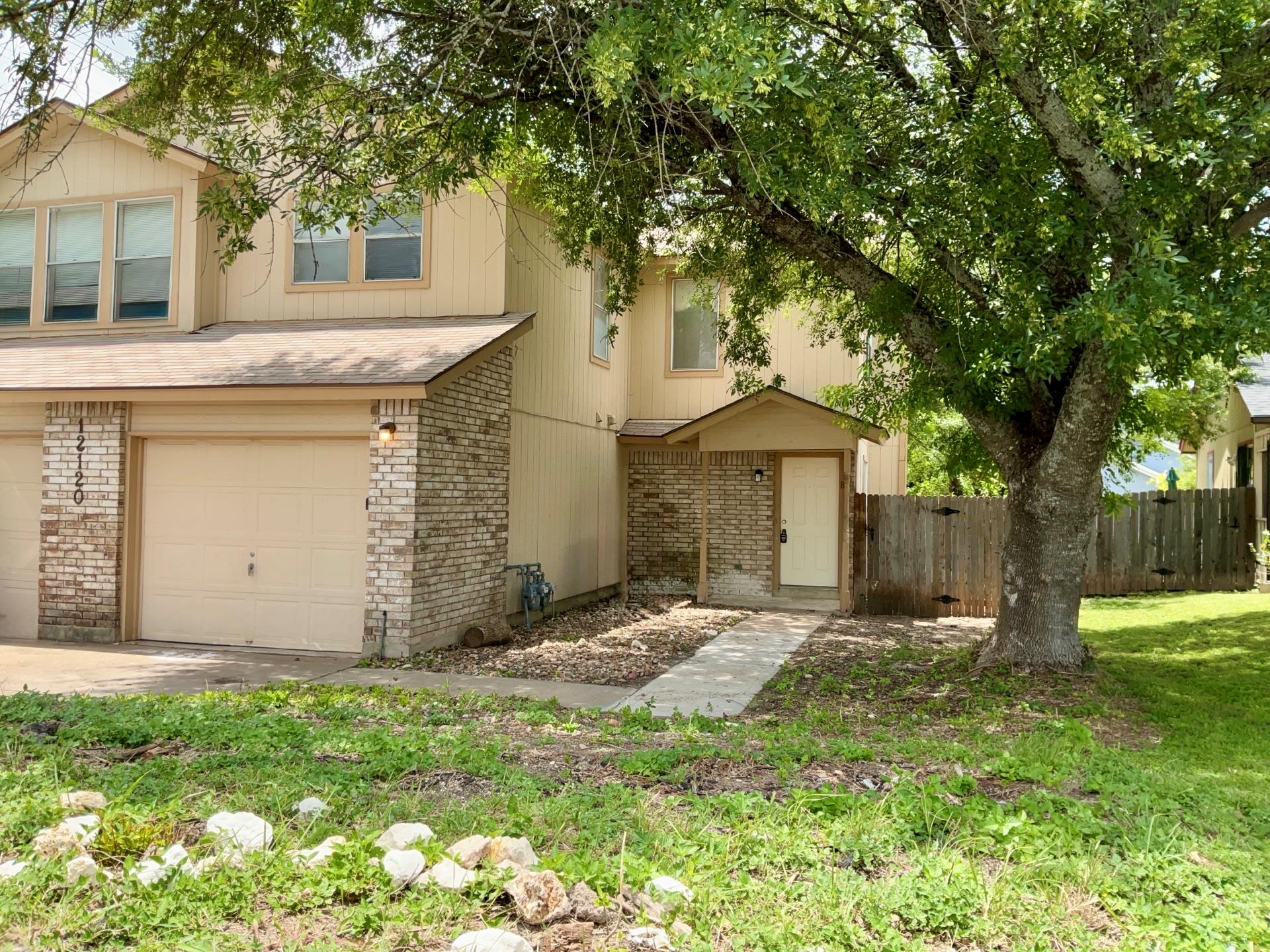 A welcoming facade with a garage and a tree-shade