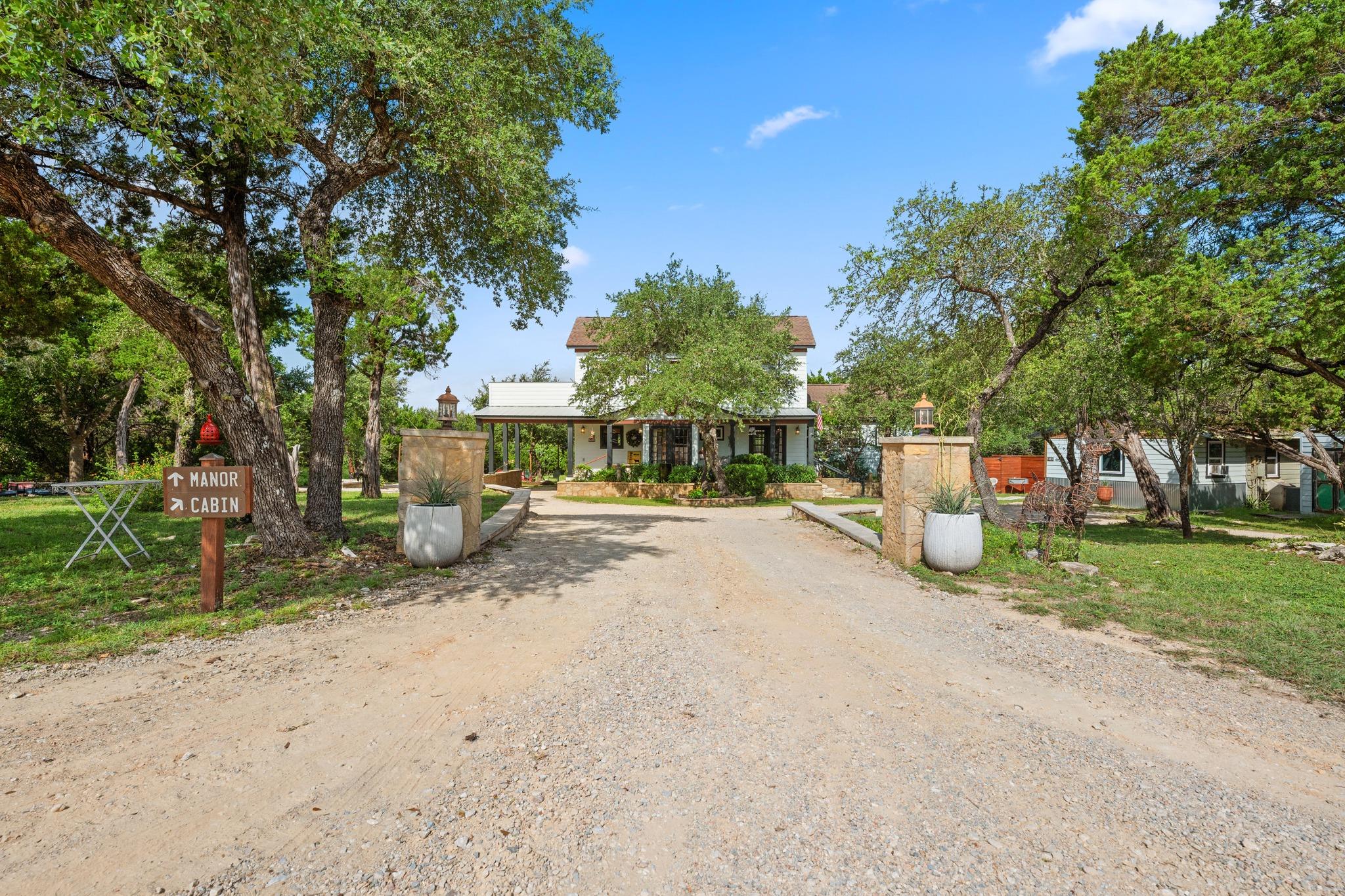 A long gravel driveway leads to a classic home ne