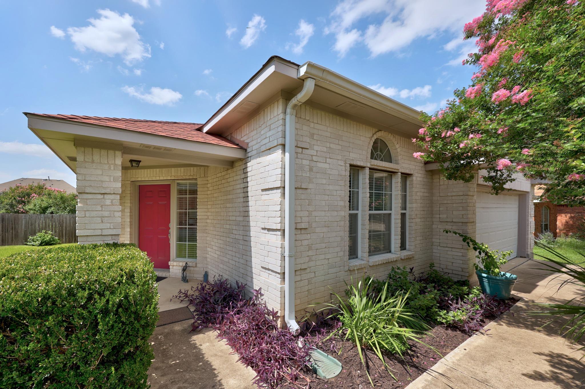 A cream brick facade welcomes with a vibrant fron