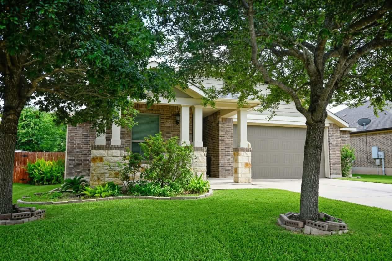 Mature trees shade a welcoming brick facade compl