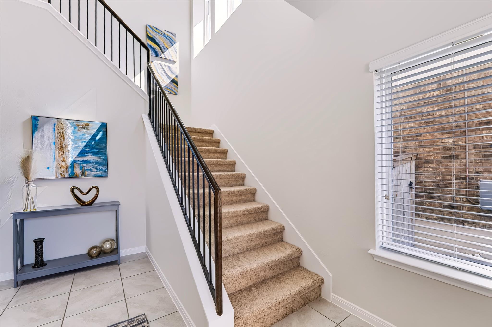 A carpeted staircase with dark metal railings asc