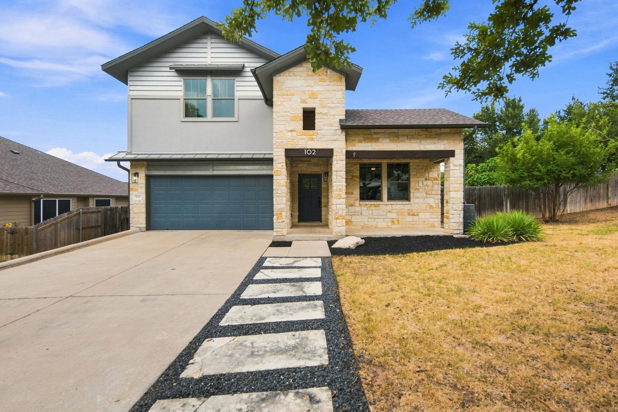 Natural stone accents and a modern walkway create
