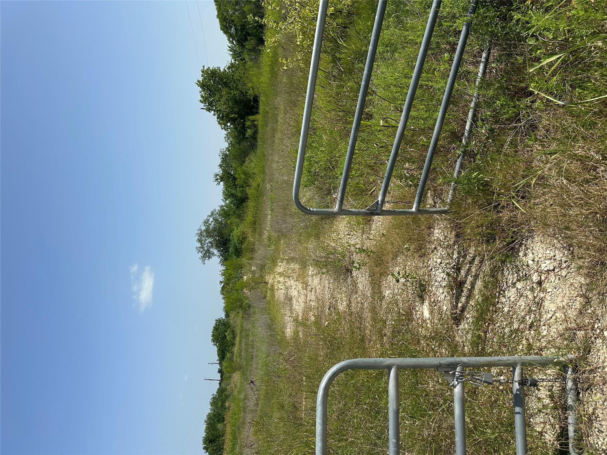 A metal gate opens to a vast, untouched rural lan