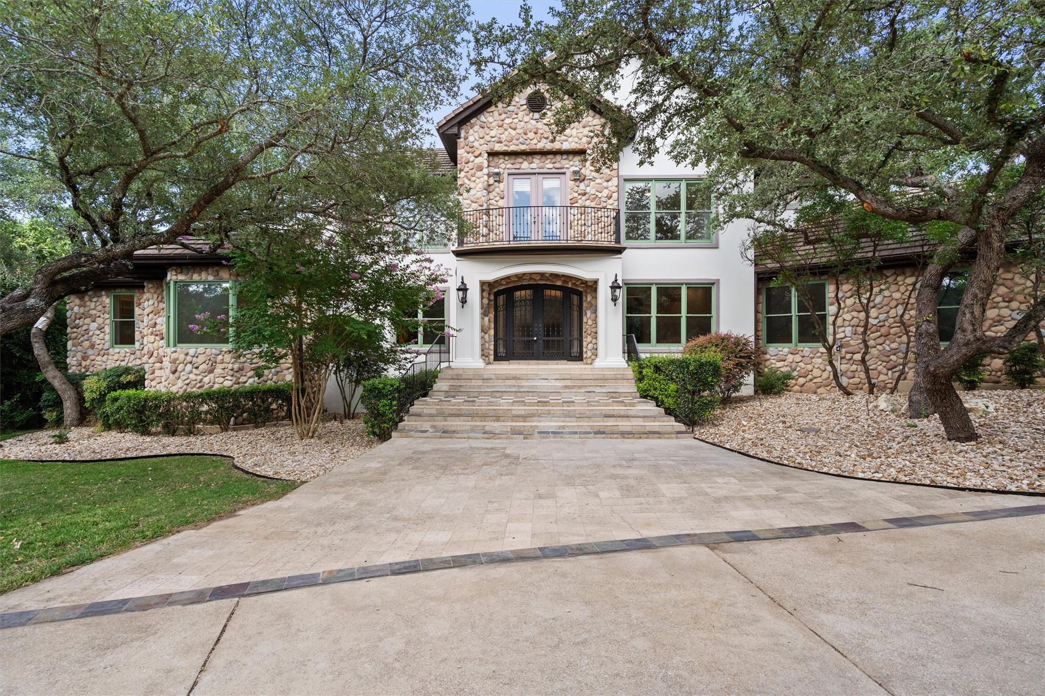 A stone and stucco facade, framed by mature trees