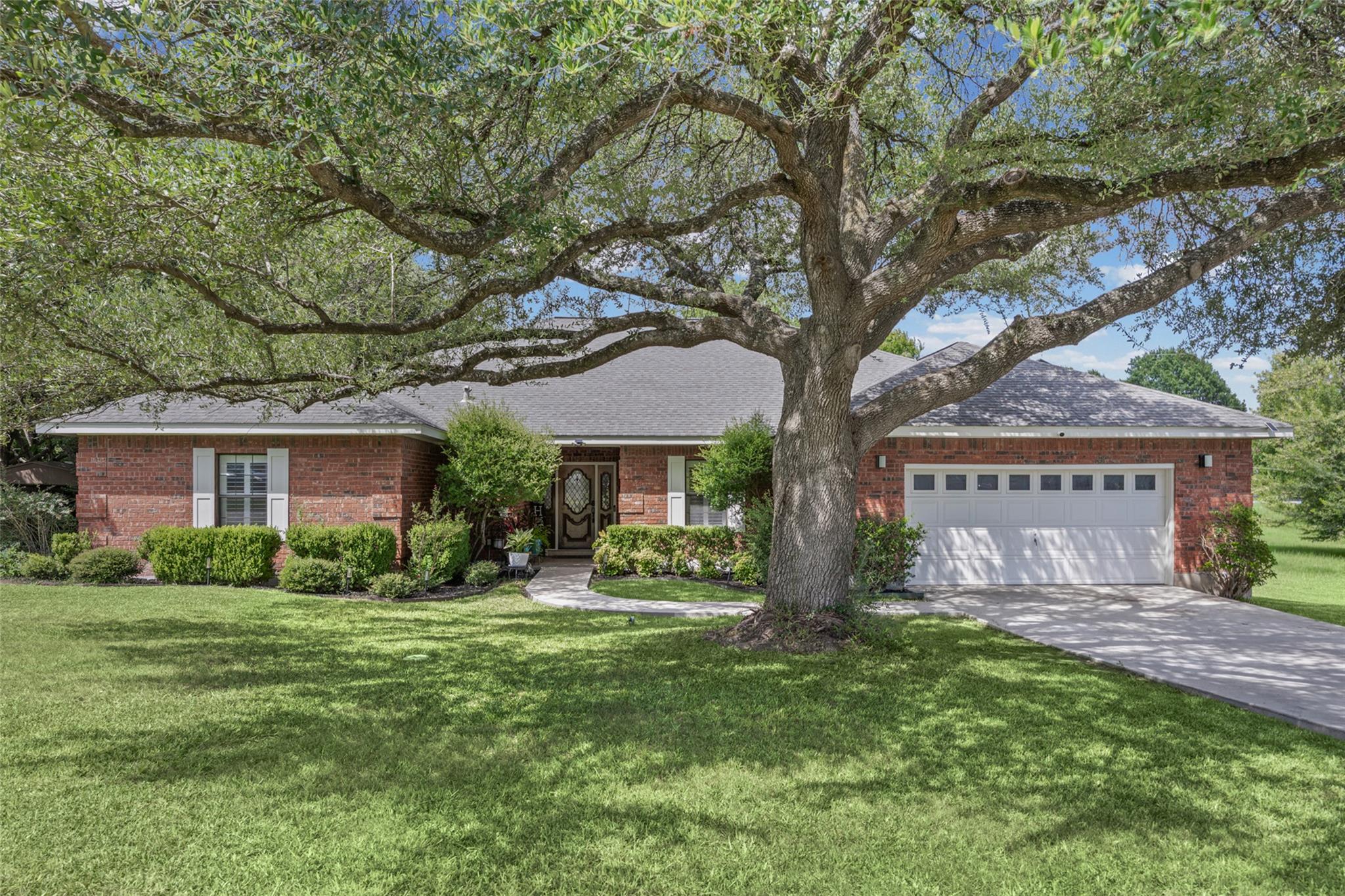 Mature trees and lush landscaping adorn this welc