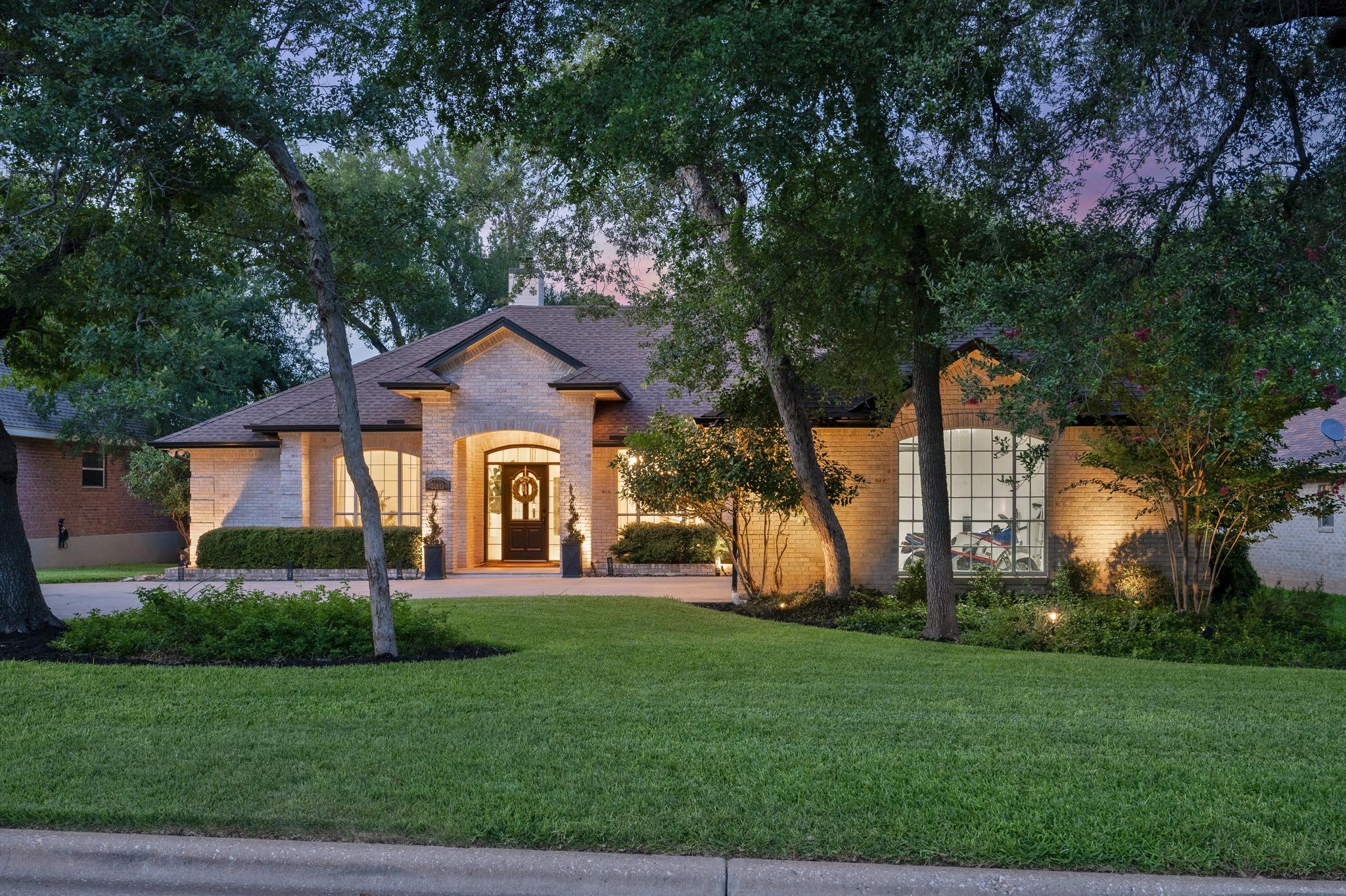 Mature trees and lush landscaping frame this eleg