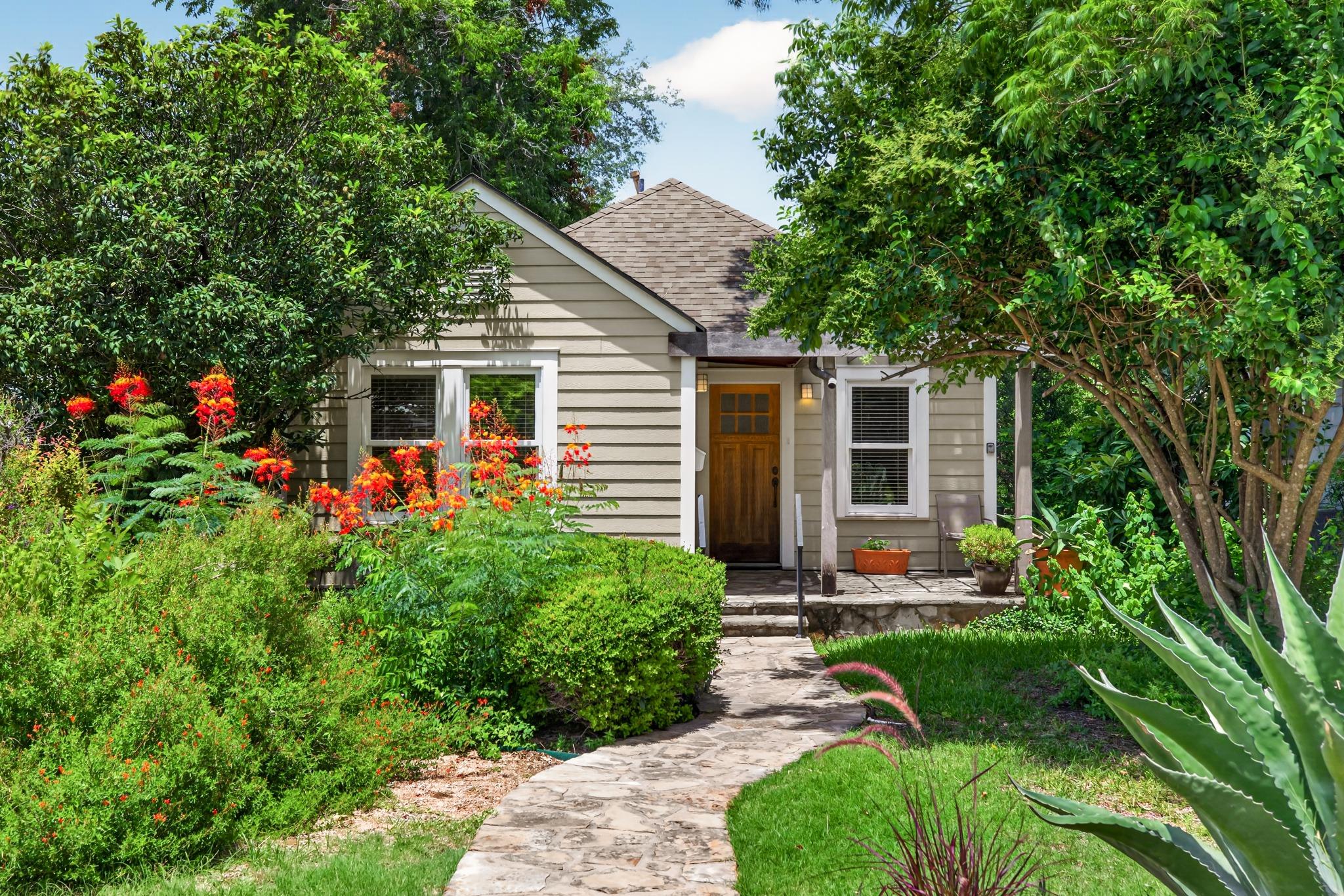 A charming cottage facade framed by mature trees 