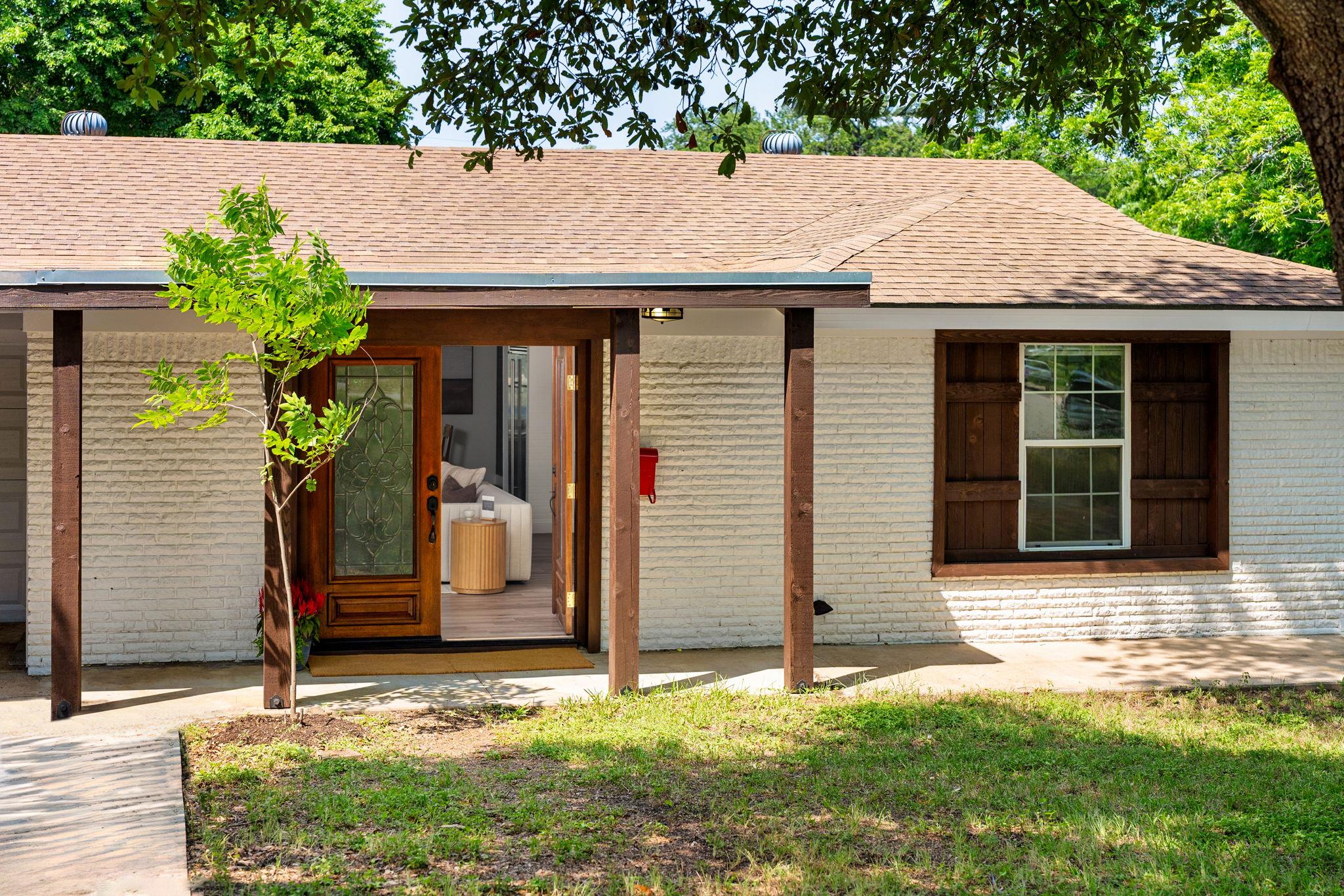 Back of house featuring brick siding and roof wit