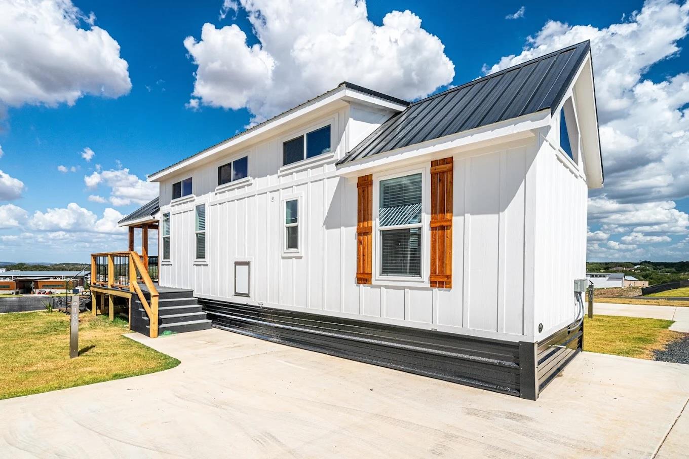 White siding with wooden shutters and a dark meta