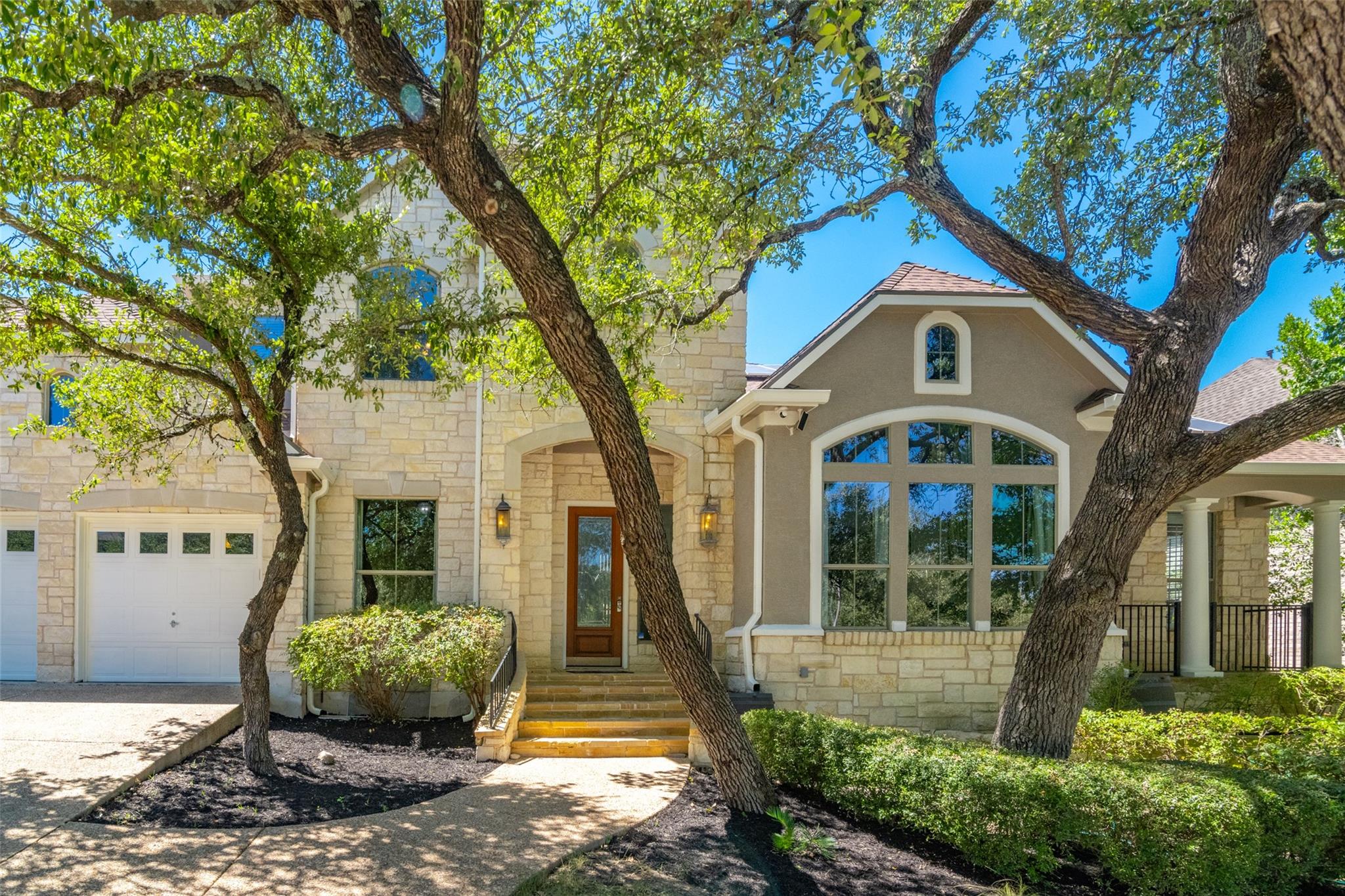 Mature shade trees frame a striking stone facade 