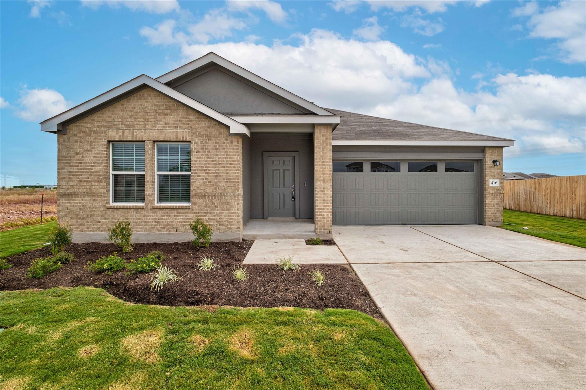 A neatly manicured lawn and garden beds frame the
