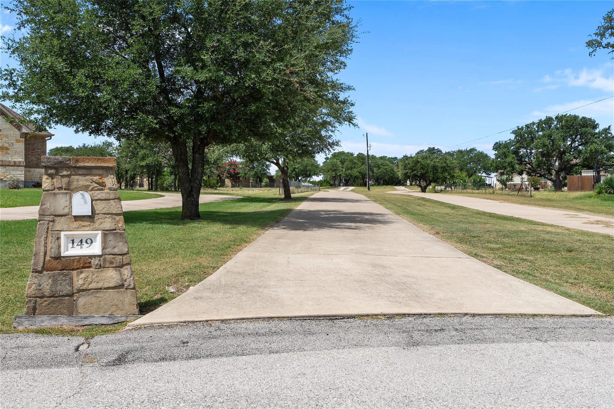 A lengthy concrete driveway leads to a property f