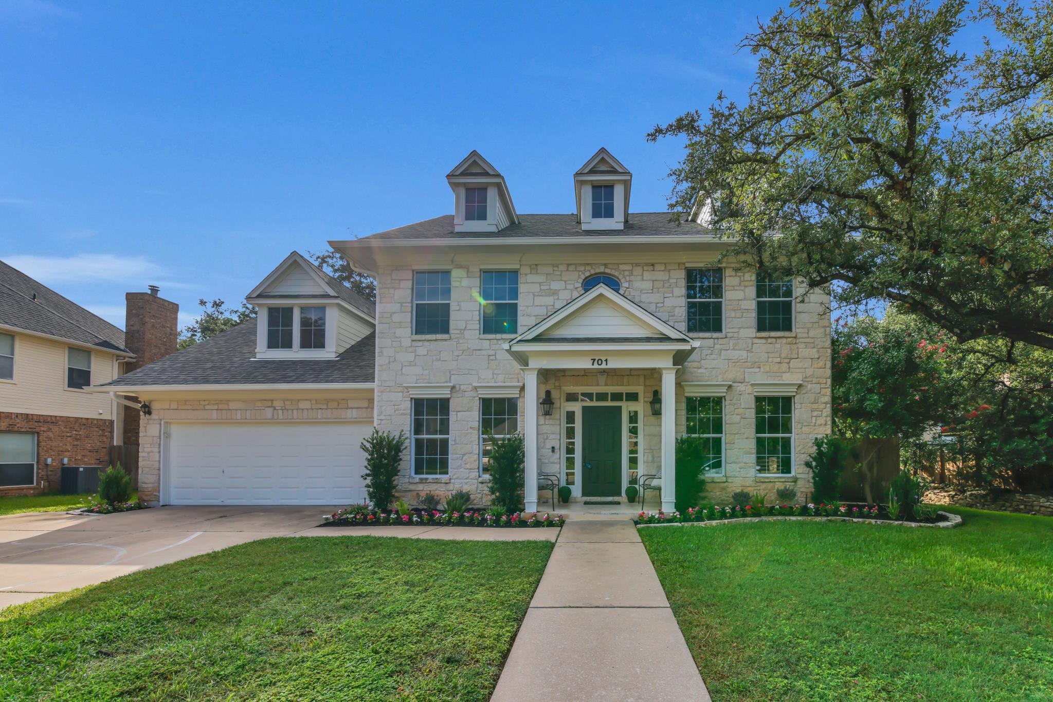 A well-manicured lawn and inviting stone facade c
