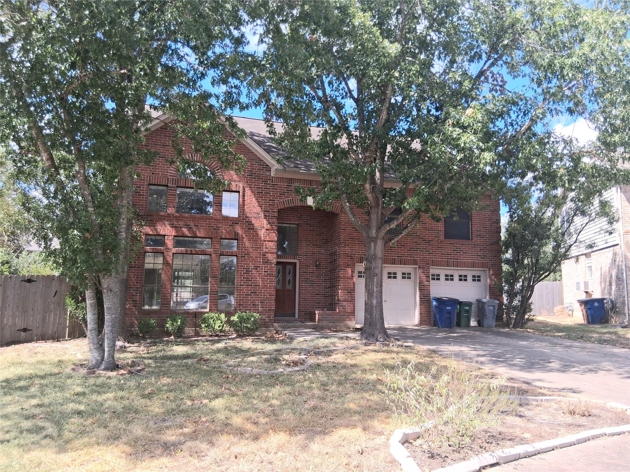 Mature trees shade a classic two-story brick exte