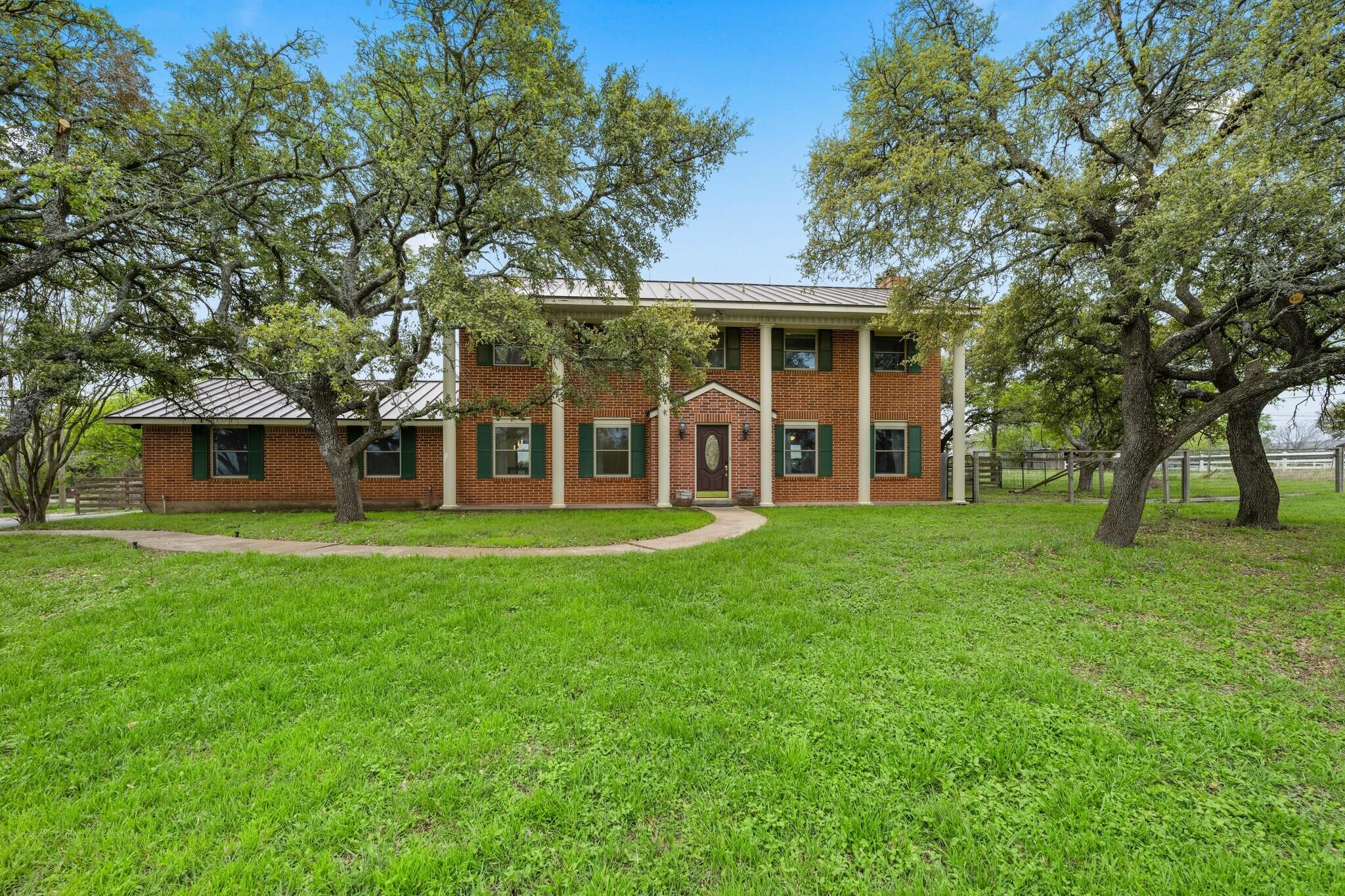 A stately brick home with a white metal roof and 