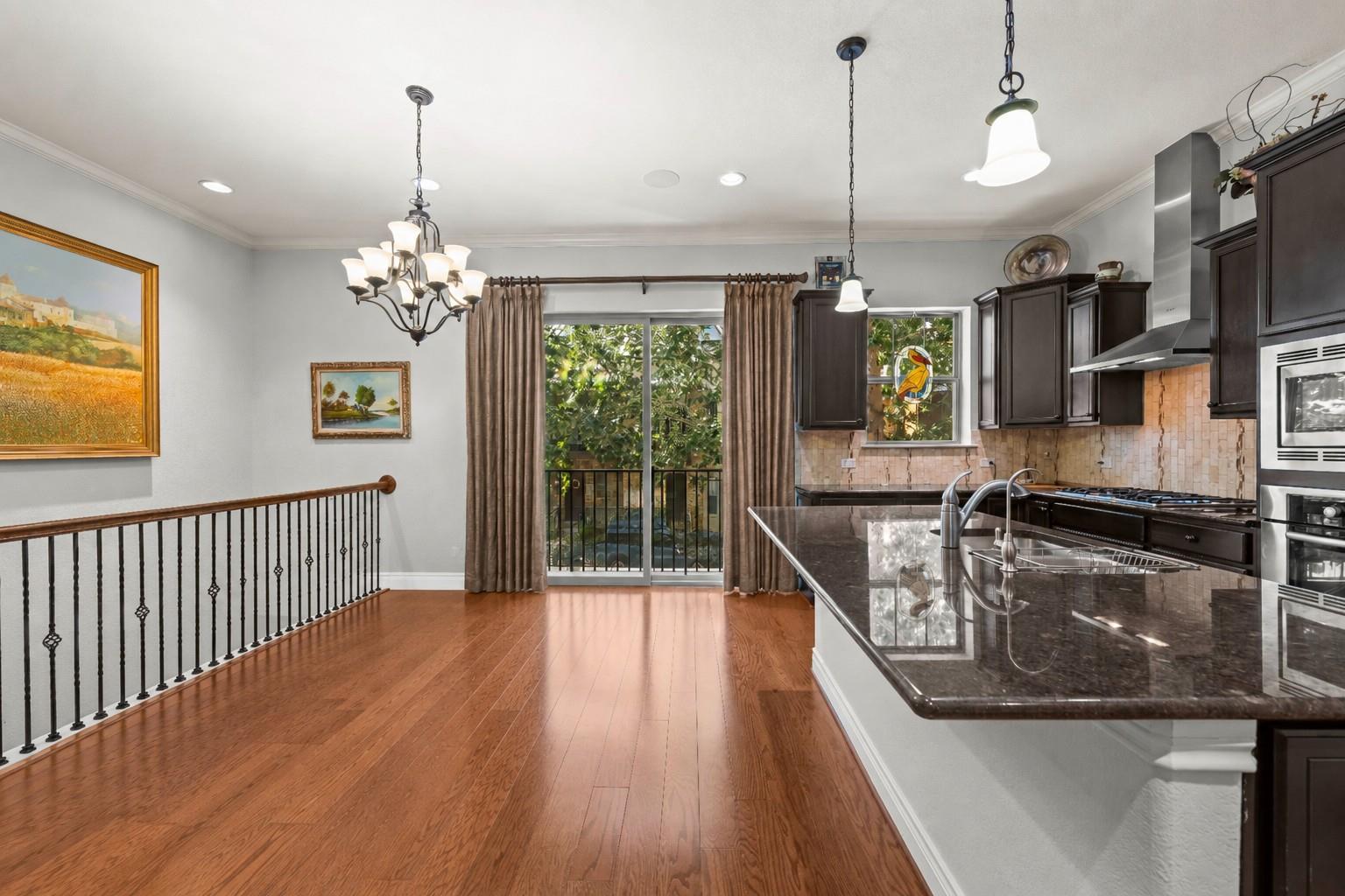 Rich hardwood floors complement dark stone counte