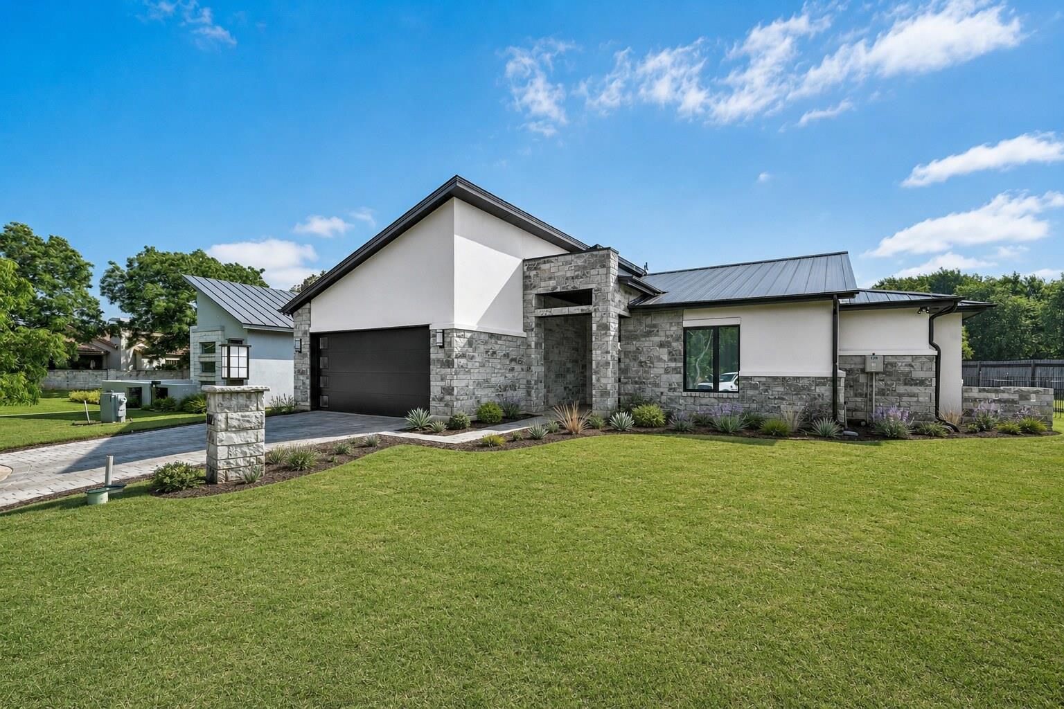 Modern stone and stucco facade with a large garag