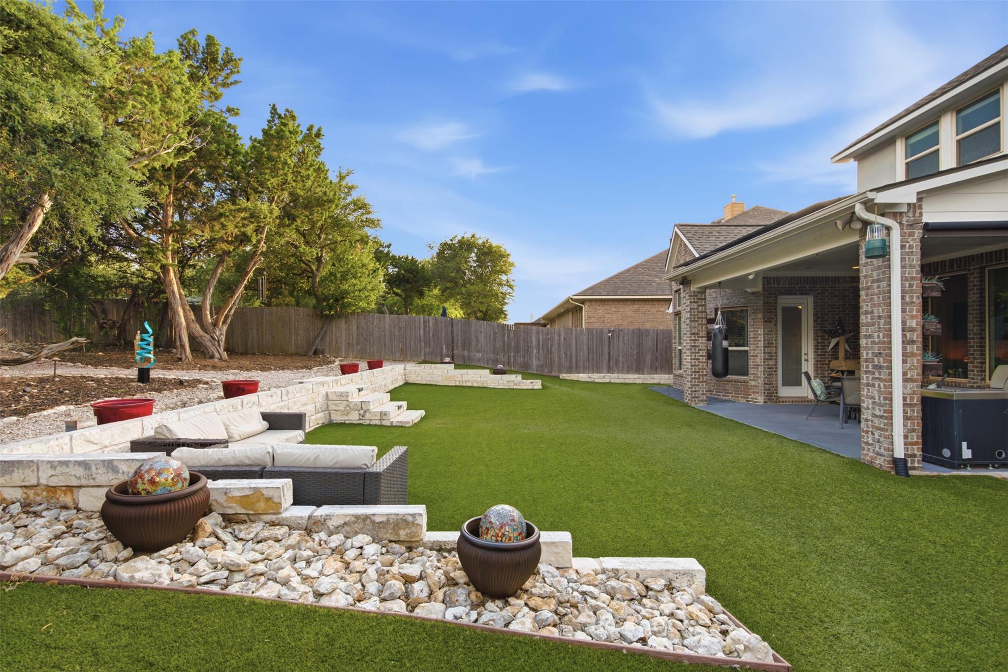 A tiered backyard retreat features artificial tur