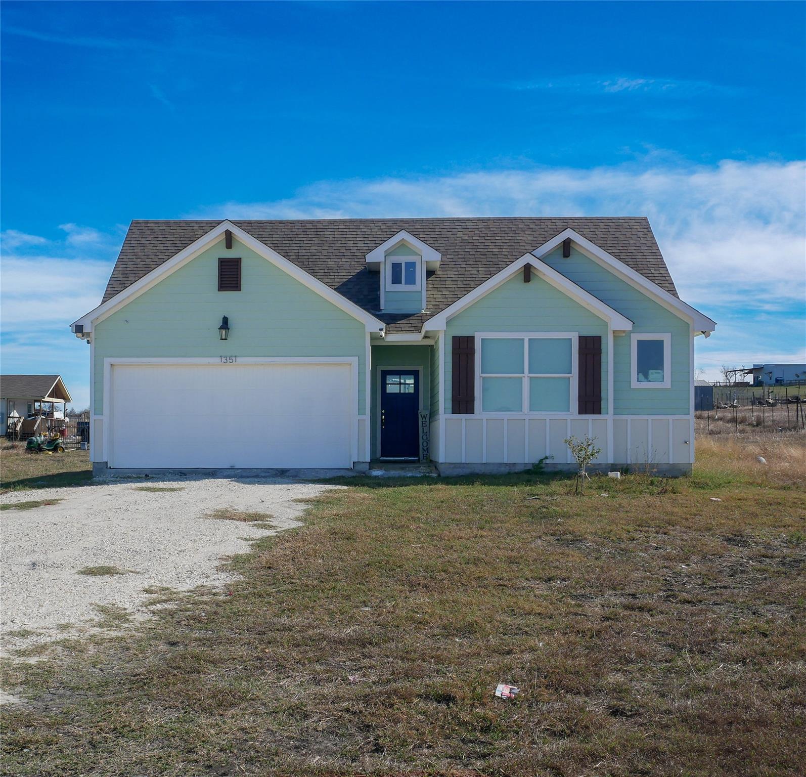 View of front of house with gravel driveway, a sh