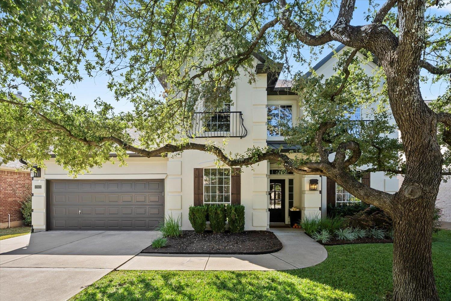 A graceful home with mature trees, a manicured la