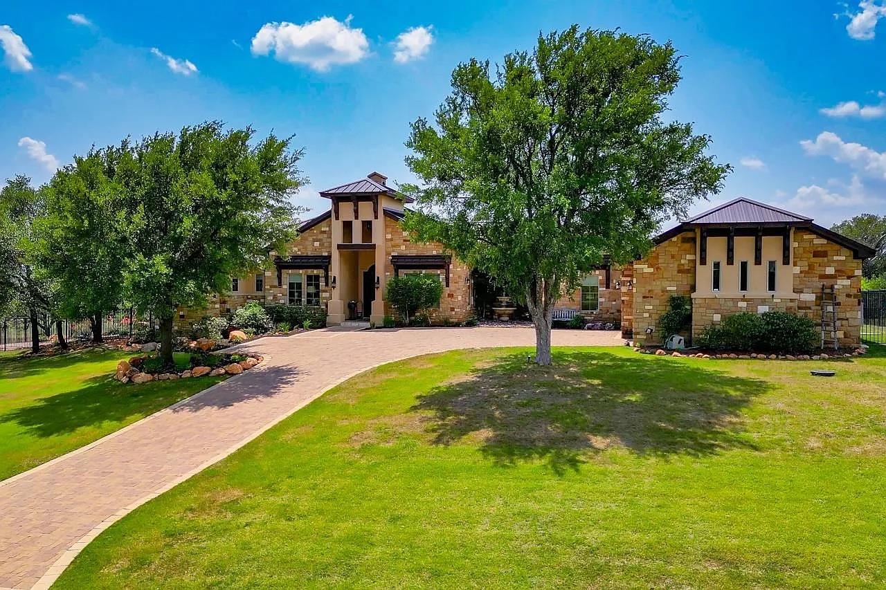 A grand paved driveway leads to a striking stone 