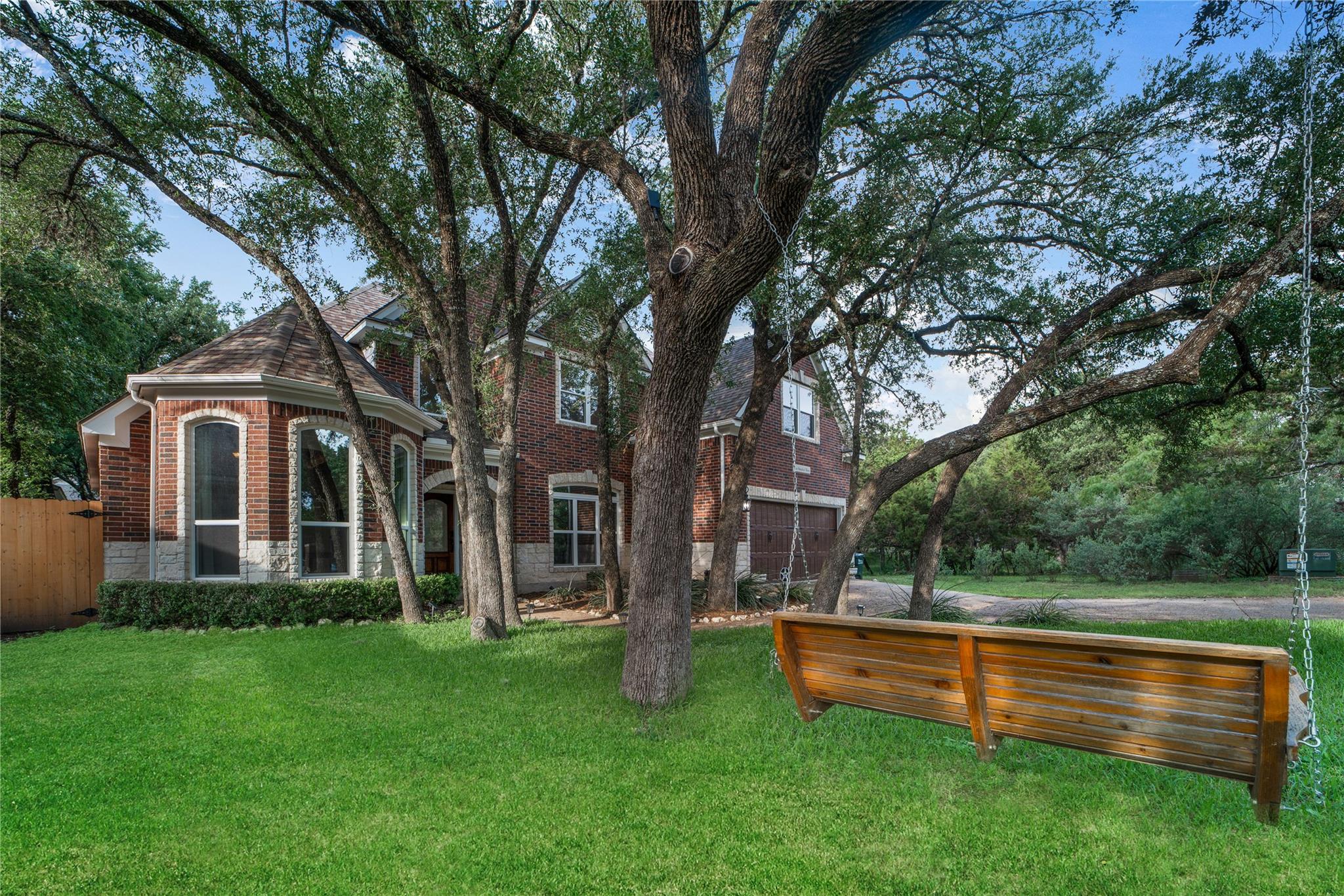 Mature trees frame this brick home, offering a ve