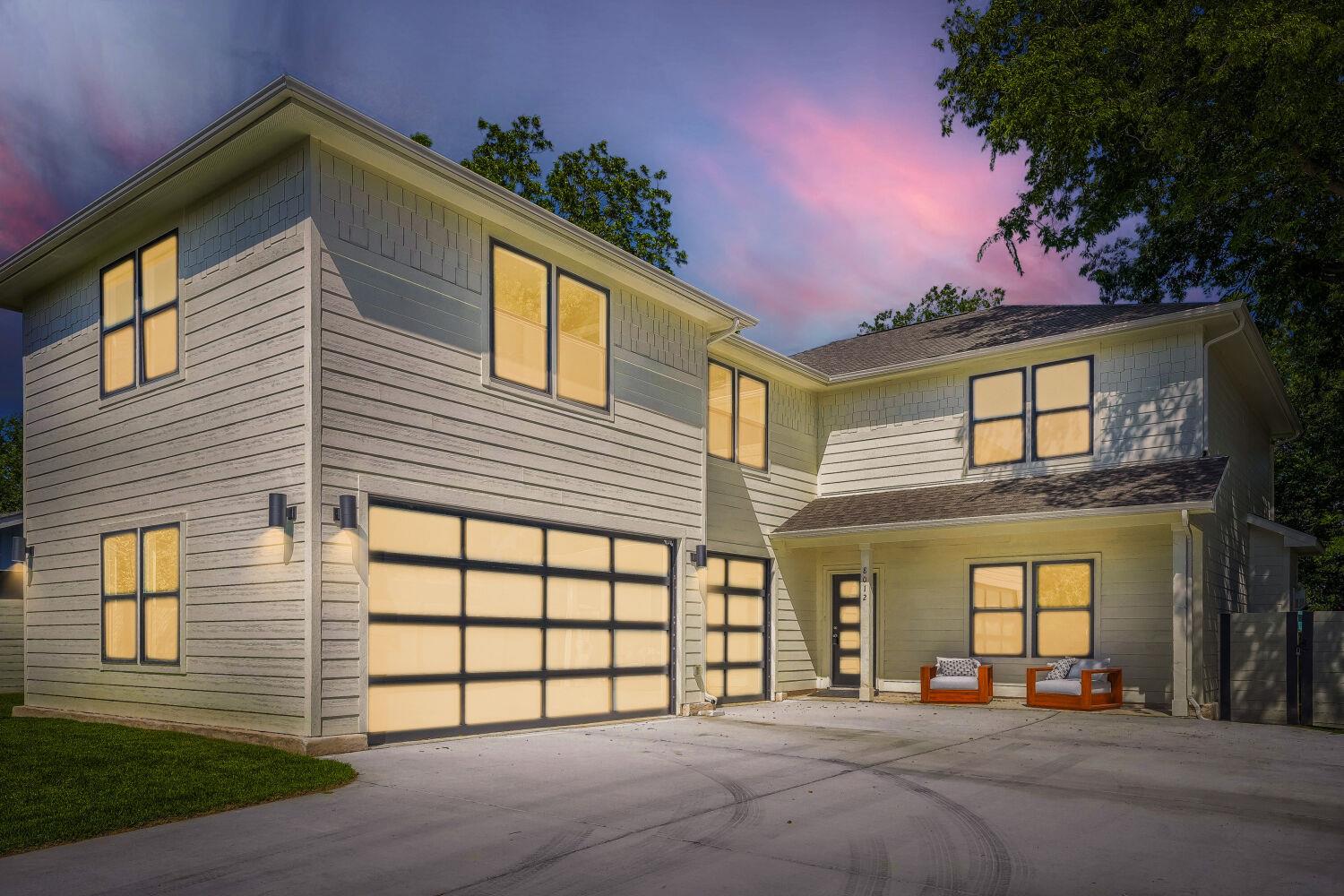A modern facade with two illuminated garage doors