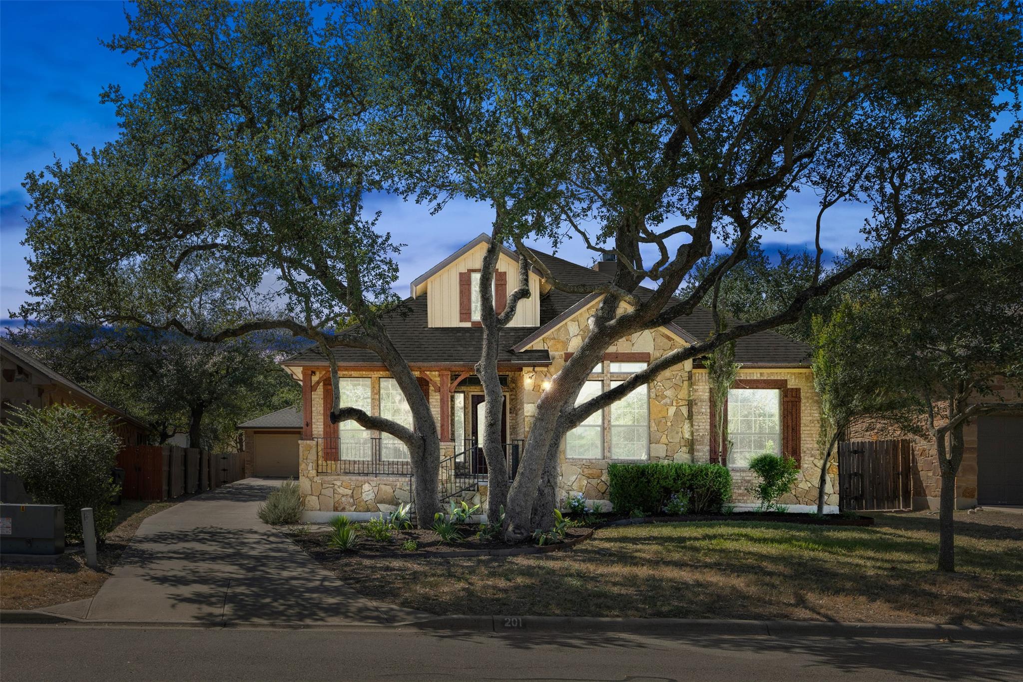 Mature oak trees frame a charming stone facade un
