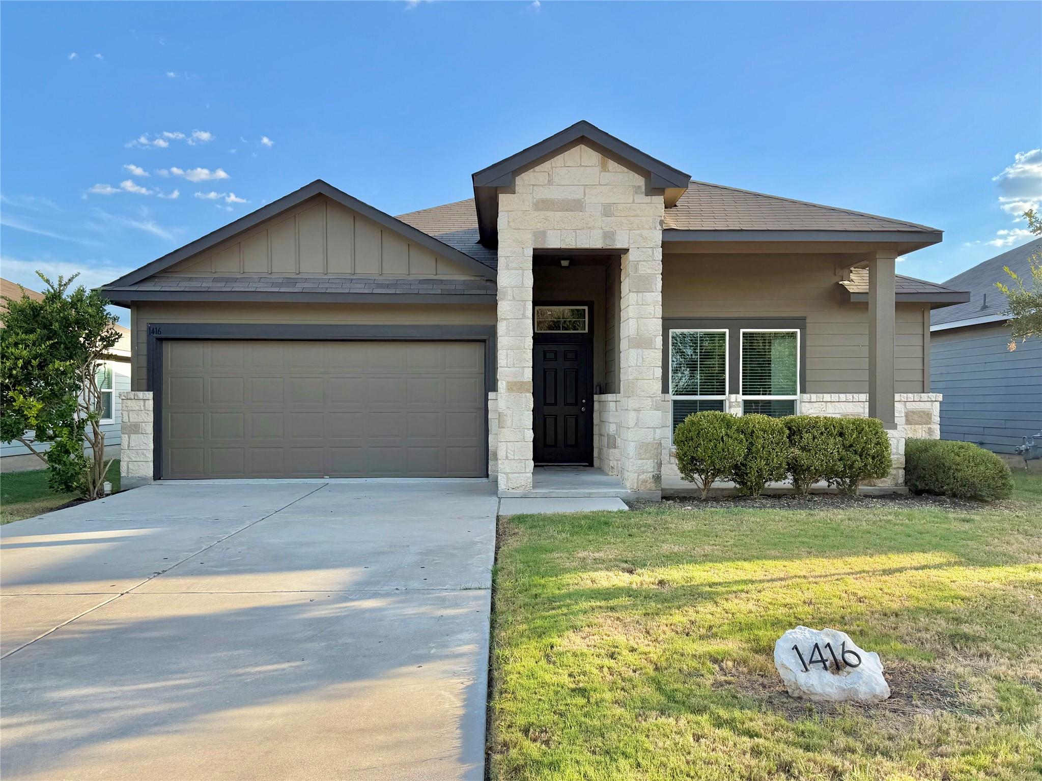 Attractive stone accents and a wide driveway crea