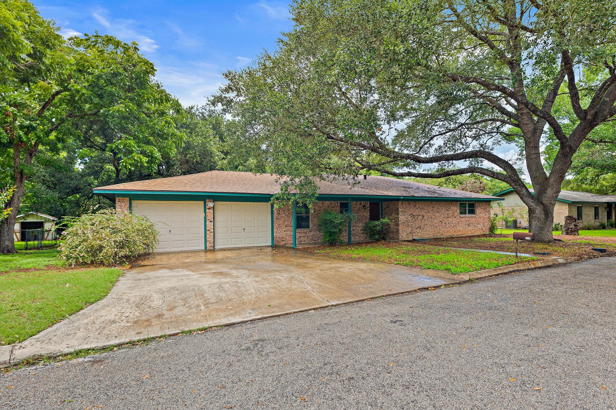 Mature trees canopy this brick residence, offerin
