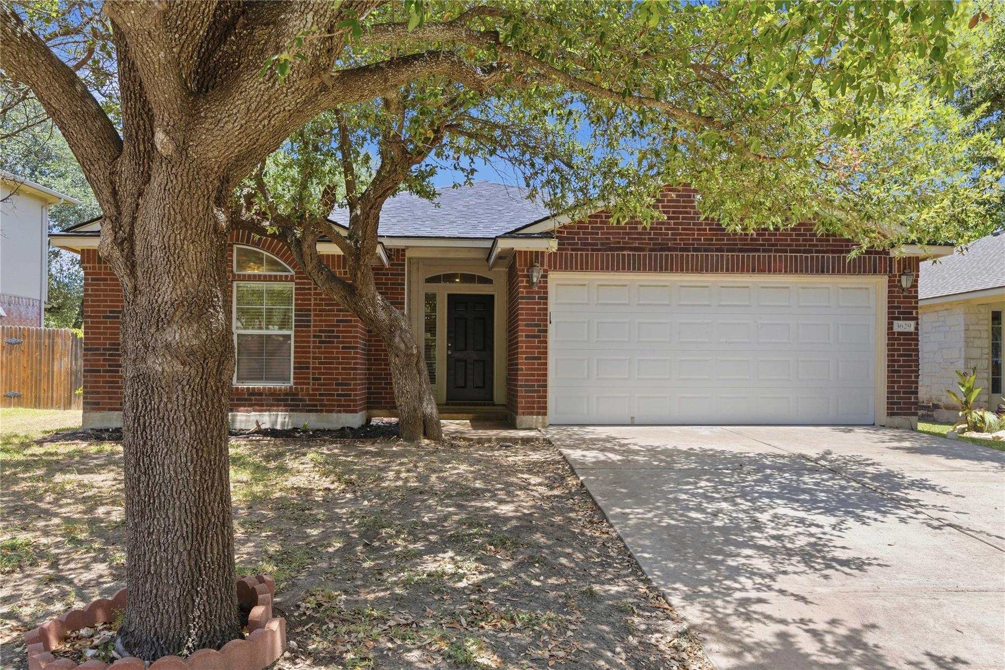 Mature trees shade this brick facade home, presen
