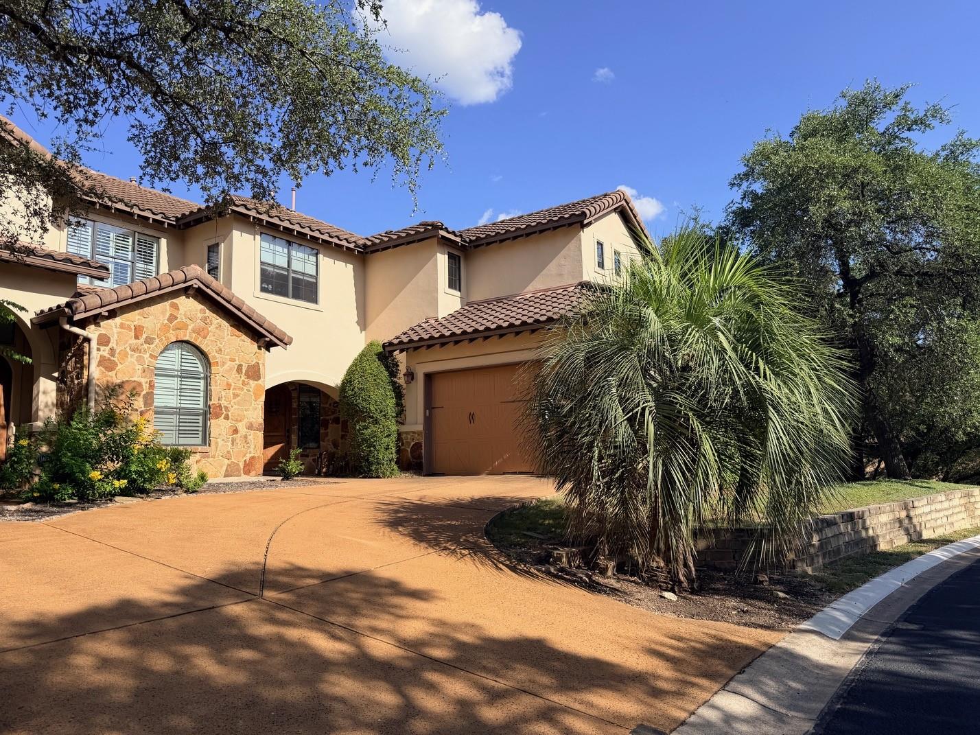 A terracotta driveway leads to a charming stucco 