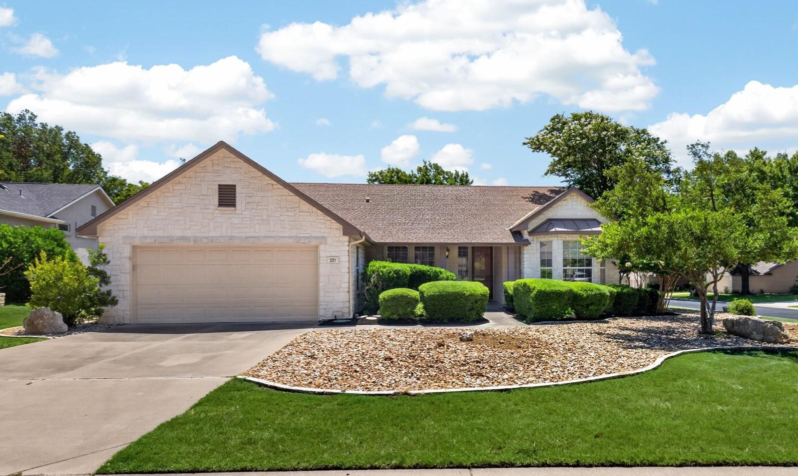 A well-kept front yard and a light-toned brick fa