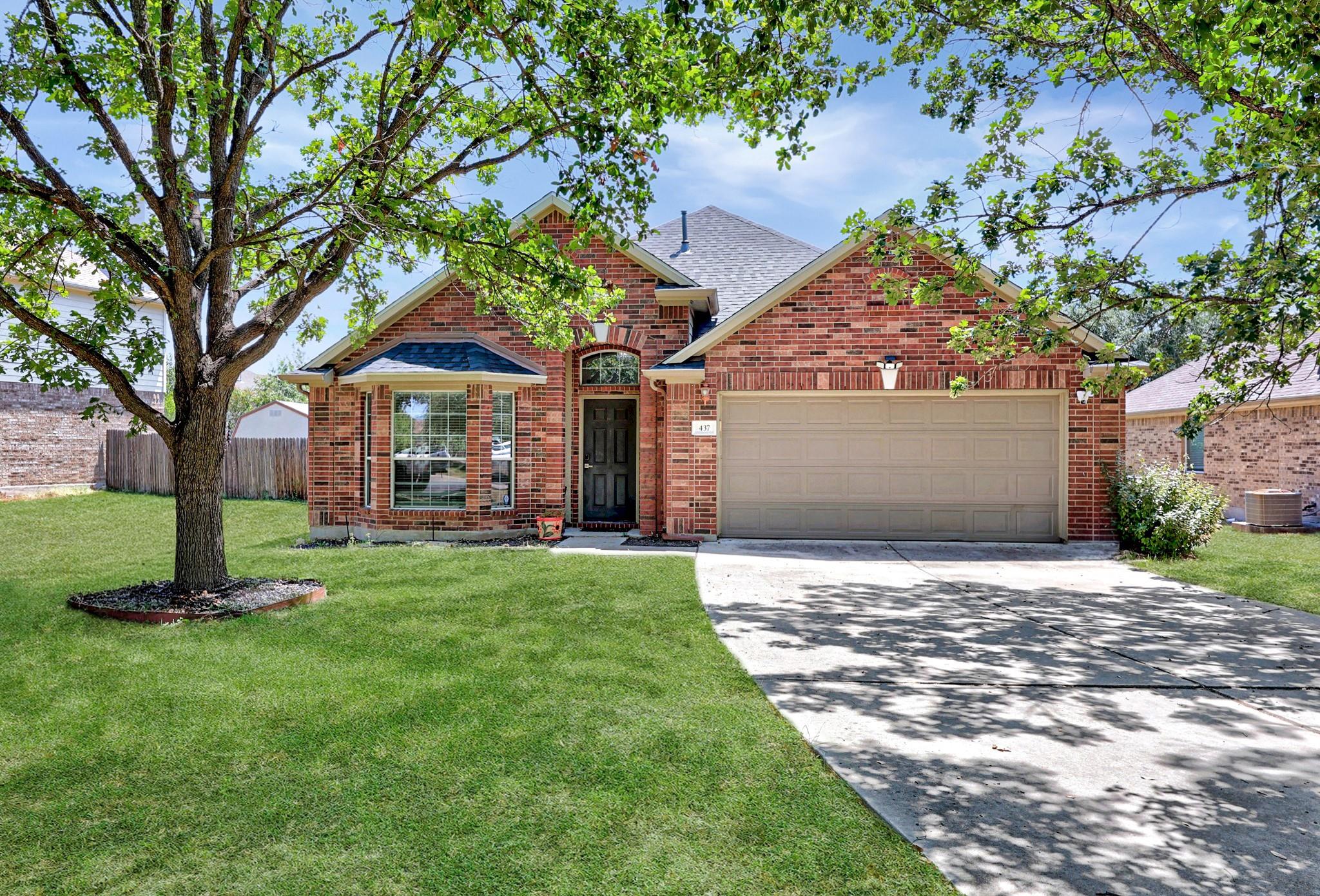 Mature trees shade a classic brick exterior compl