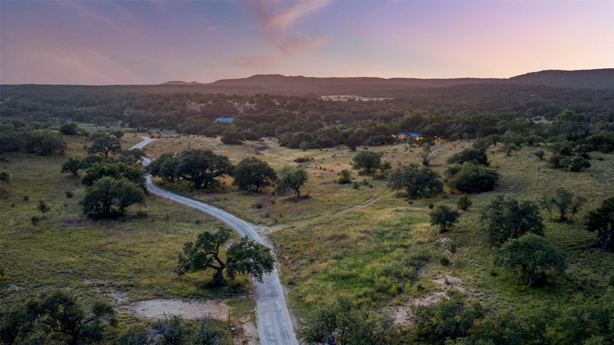 Vast, verdant landscape with a winding driveway l