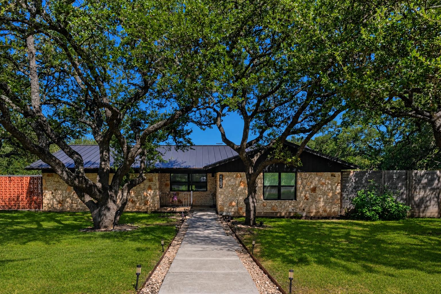 Mature trees shade this charming stone-clad home,