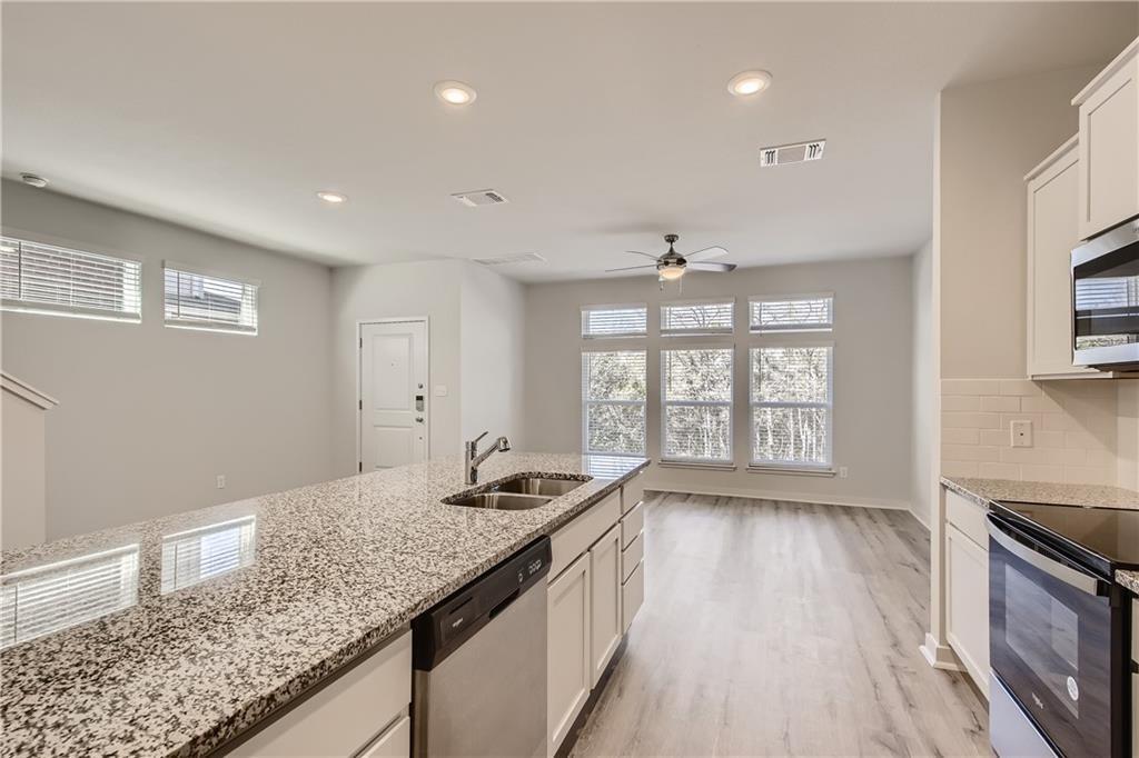 A well-lit kitchen with granite counters opens to
