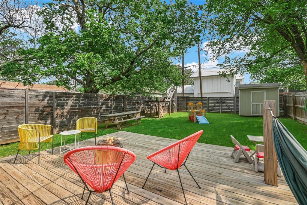 A spacious backyard features a wooden deck, a gre