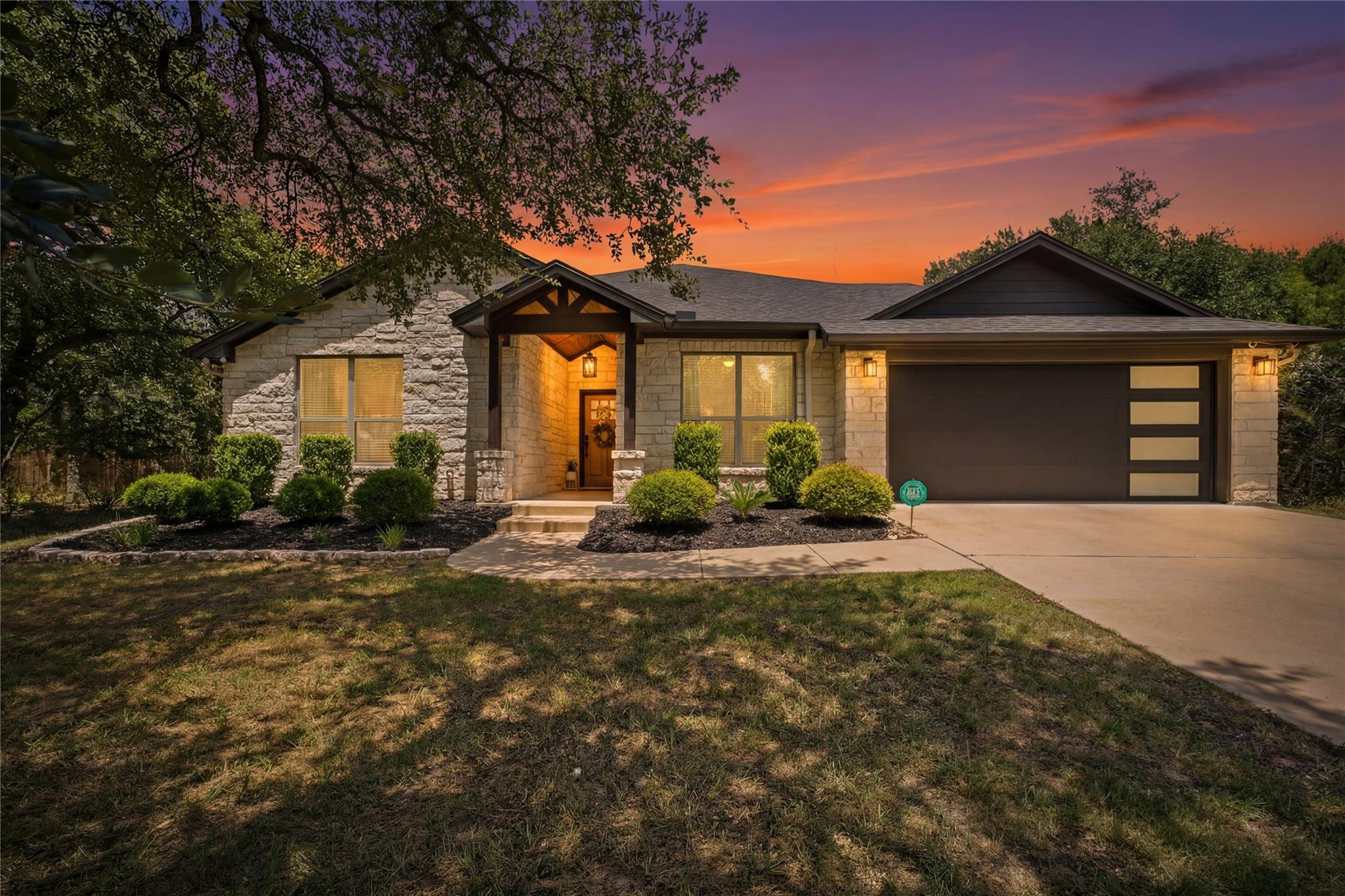 A striking modern stone home with a dark garage d