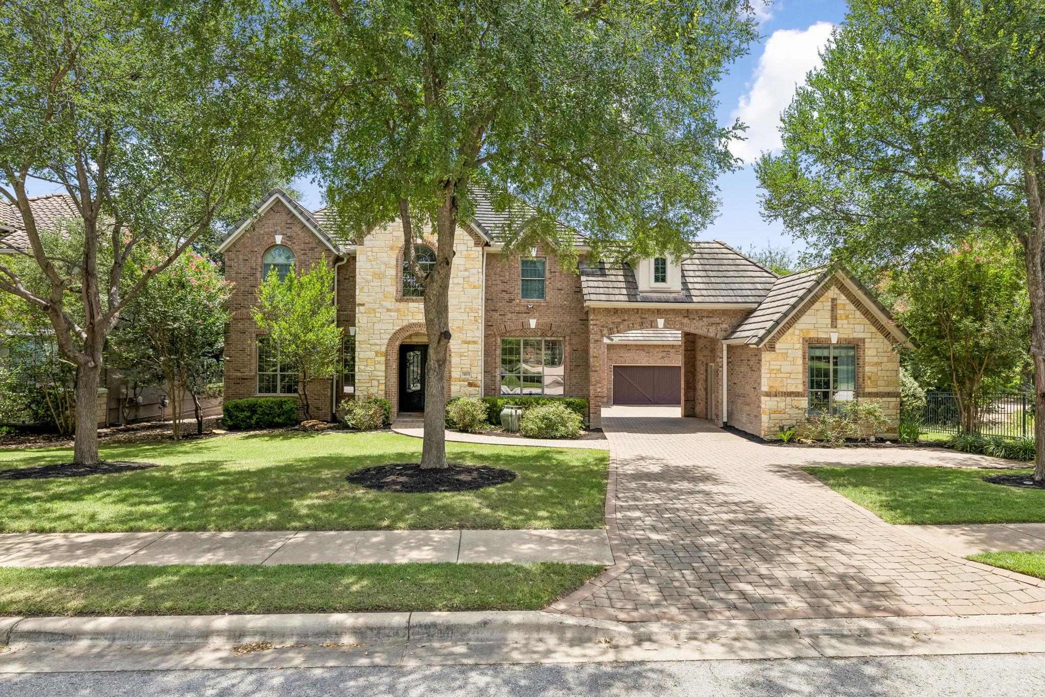 A stately brick and stone residence, framed by ma