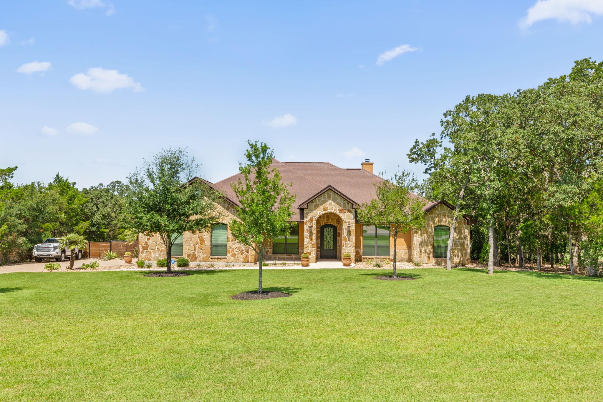 A classic stone facade and mature landscaping def