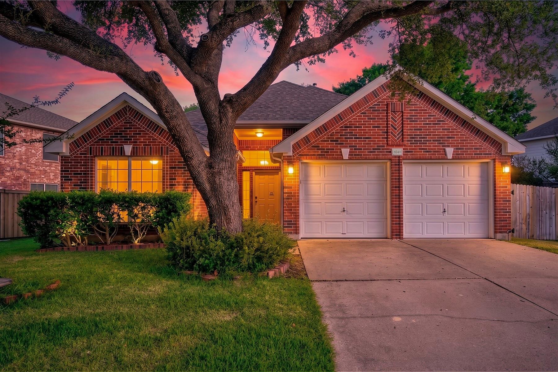 Mature trees frame this inviting brick facade wit