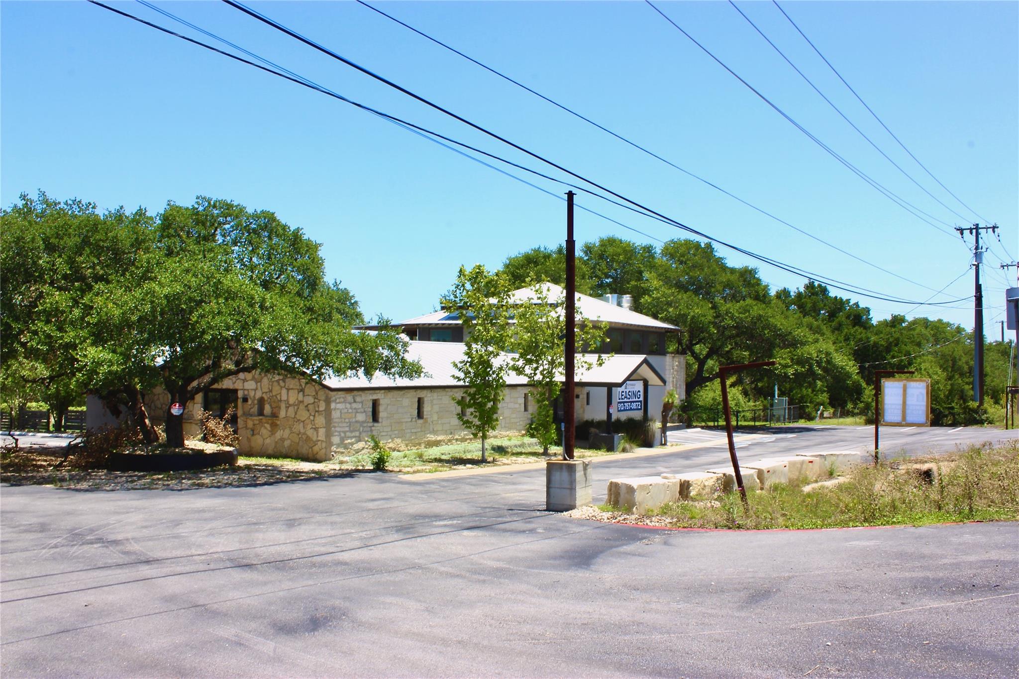 A stone and stucco structure with abundant trees 