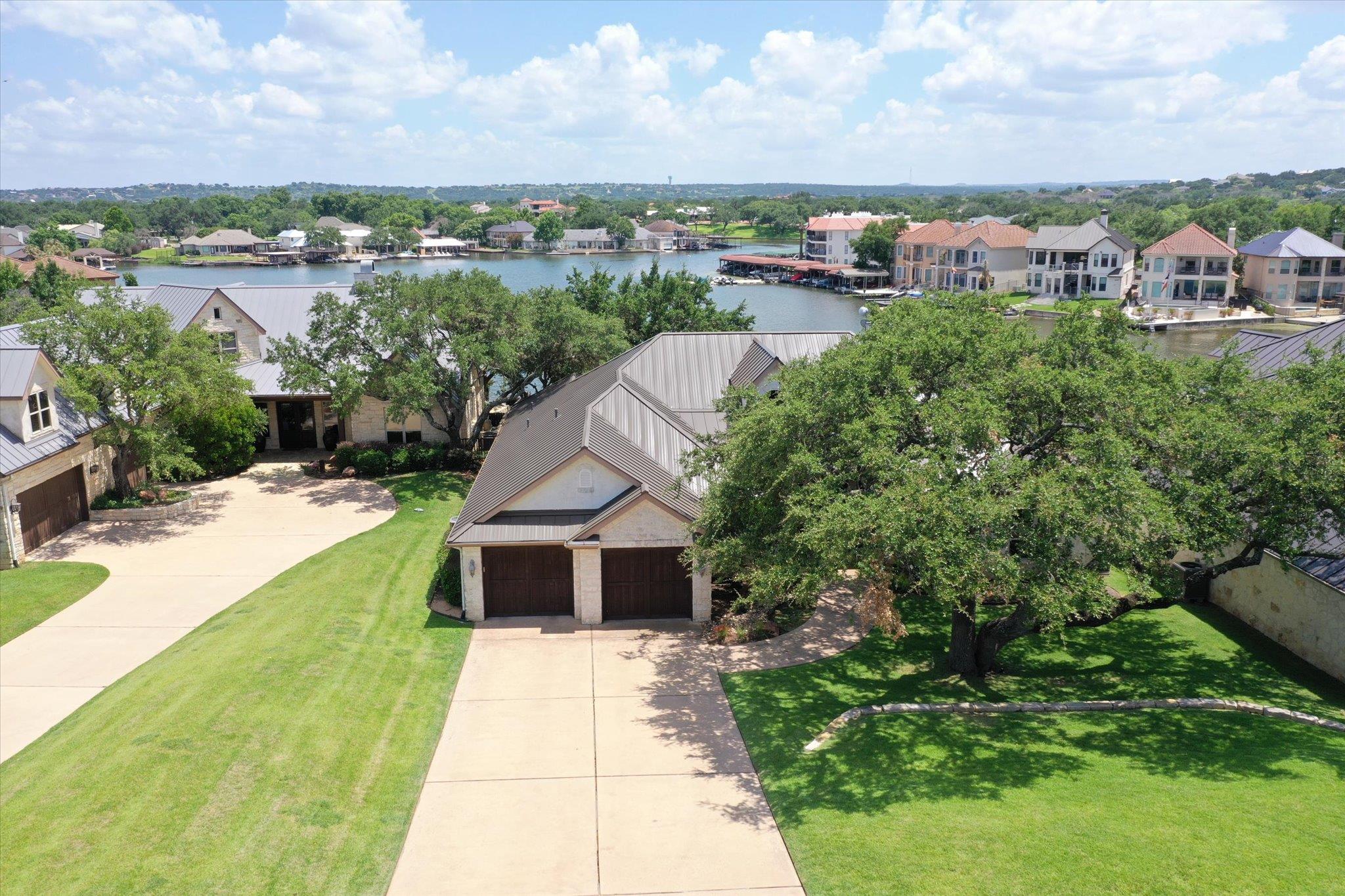 Mature shade trees flank a concrete driveway lead