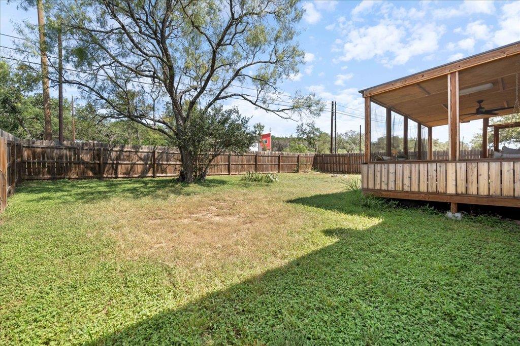 A spacious backyard with mature trees and a fence